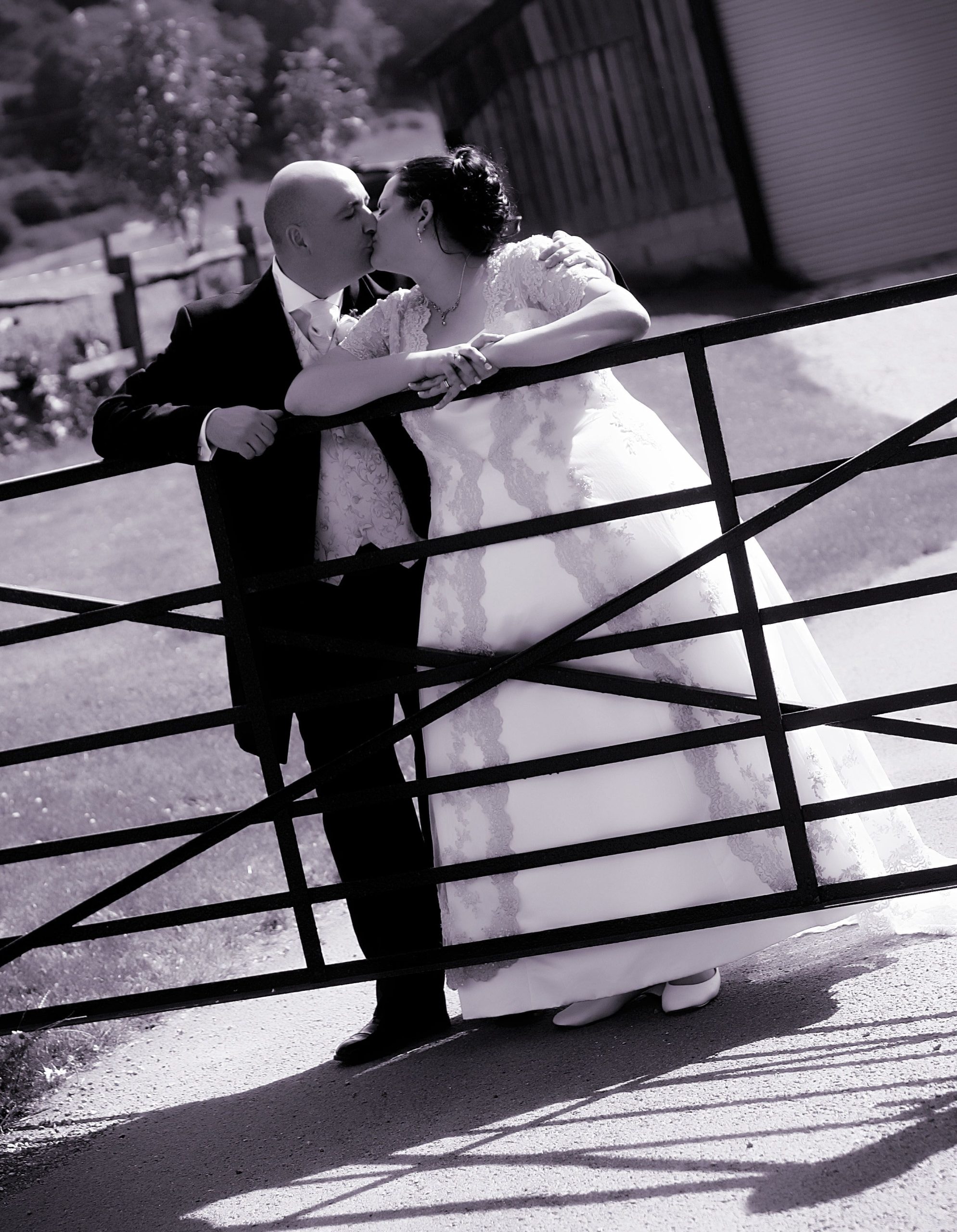 a man and woman kissing on a fence
