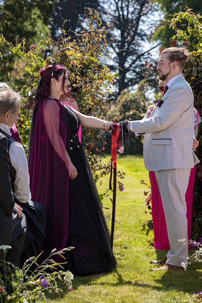 Couple exchanging vows in garden setting.
