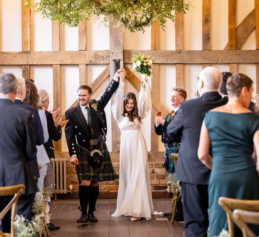 Couple celebrating wedding ceremony at Gatestreet Barn joyfully.