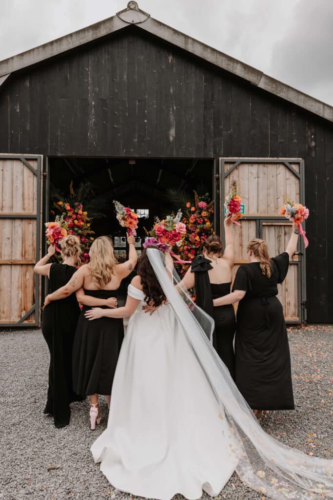 Bridesmaids celebrating outside a barn.