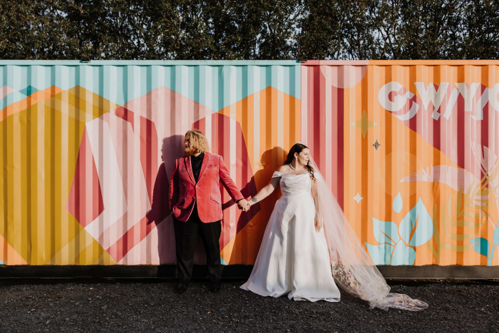 Couple holding hands by colourful containers.