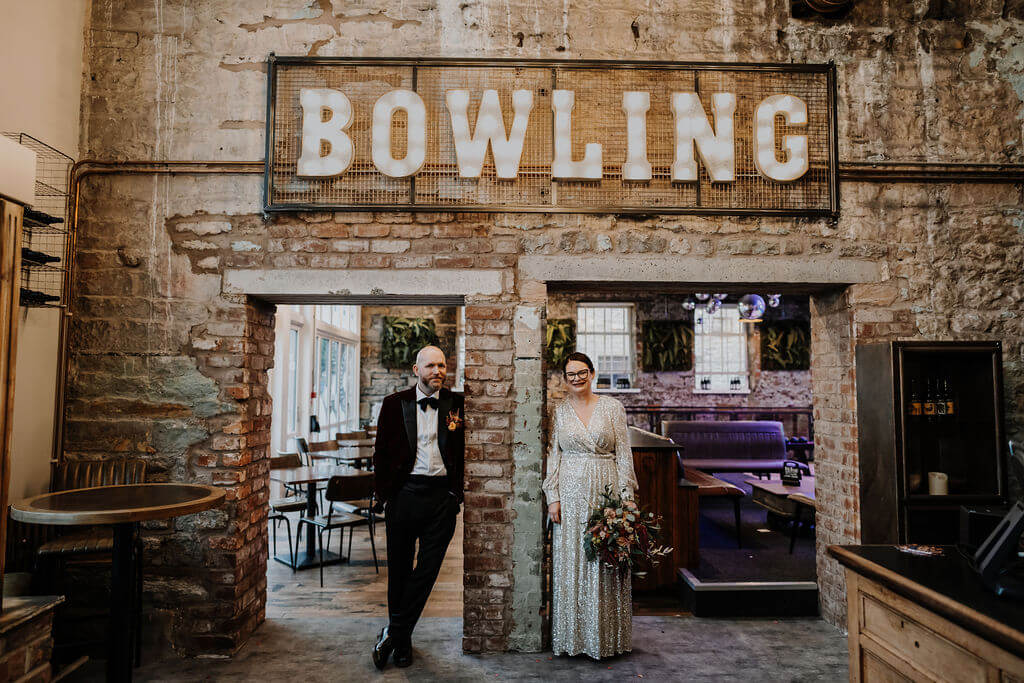 Couple posing under a bowling sign.