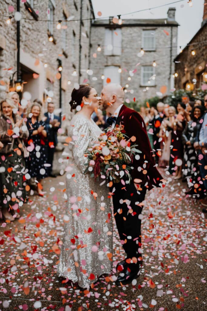 Couple kissing amidst confetti celebration.